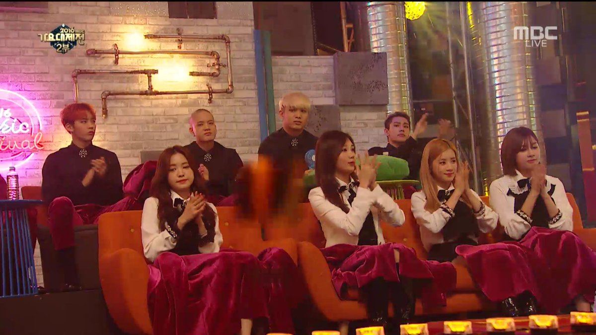 Apink sitting down with BTOB's jackets on their laps