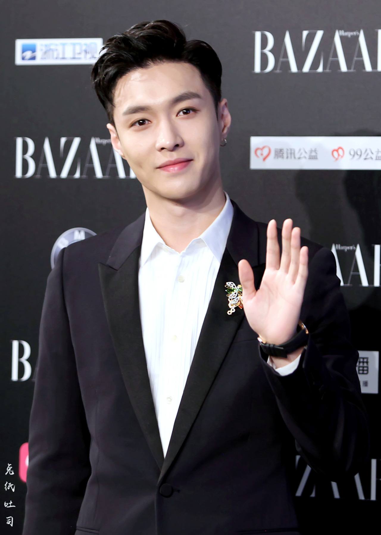 Lay de EXO sonrió a los aficionados mientras posaba para una foto en Harper Bazar Evento. 